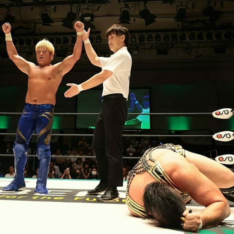 Dos luchadores en un ring de lucha libre celebrando la victoria.