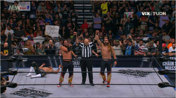 The Young Bucks y The Gunns, se enfrentan en un ring de lucha libre con un árbitro.