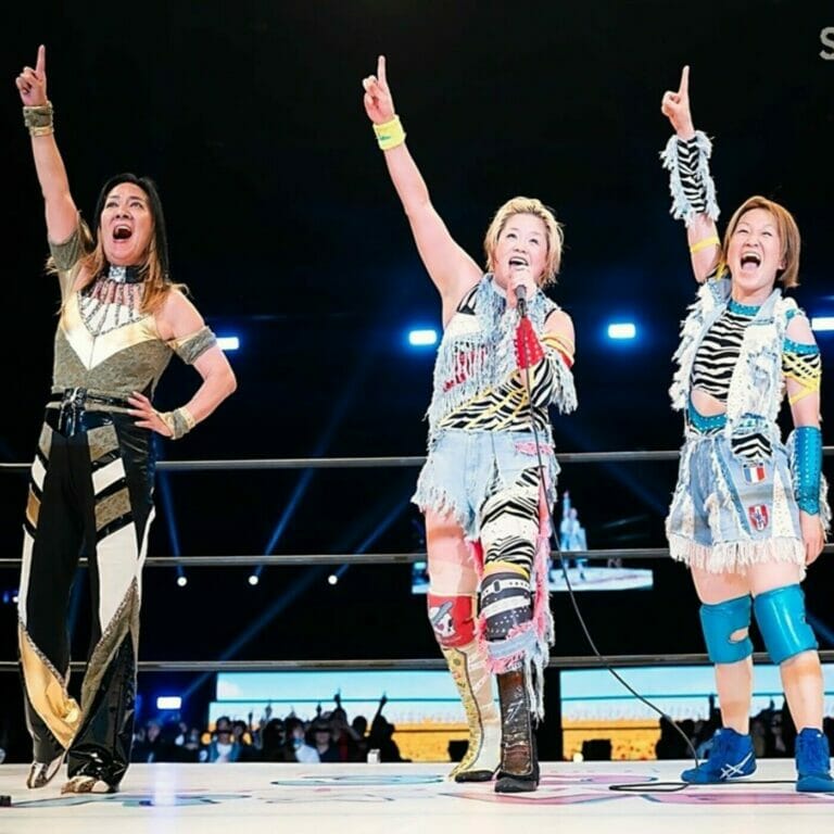 Tres luchadoras en el "Midsummer Fest 2023" de Stardom levantan triunfalmente sus manos en el aire.
