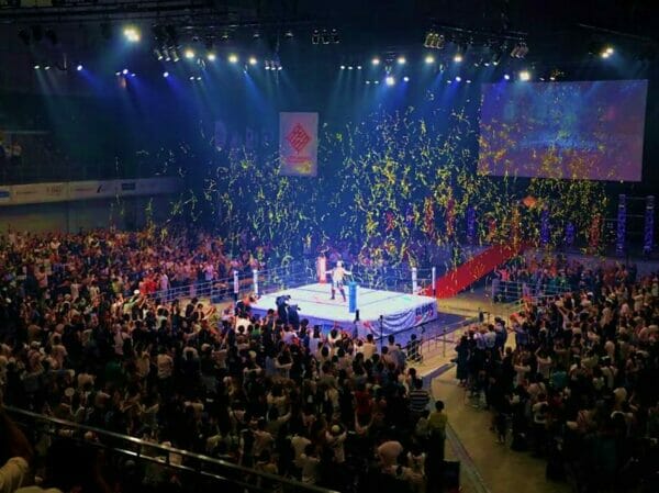 Una función concurrida celebra los 15 años de Kyushu Pro con una multitud de personas en un gran estadio.