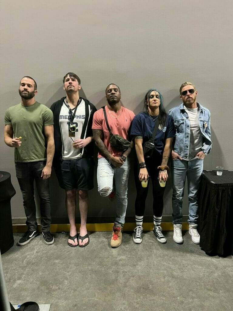 Superluchas - Un grupo de personas paradas frente a una pared, prometiendo convertirse en campeones y representando a AEW.