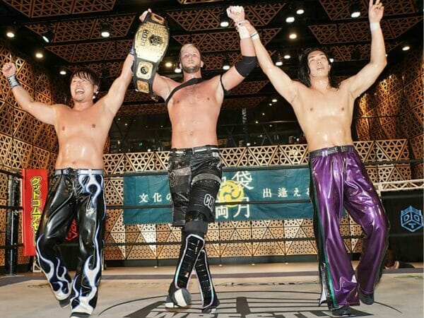 Superluchas - Un grupo de hombres levantando los puños en un ring de lucha libre en el evento DDT.