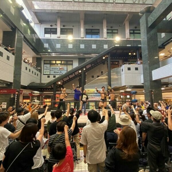 Una multitud de personas viendo un combate de lucha libre en un centro comercial durante el campeonato BJW.