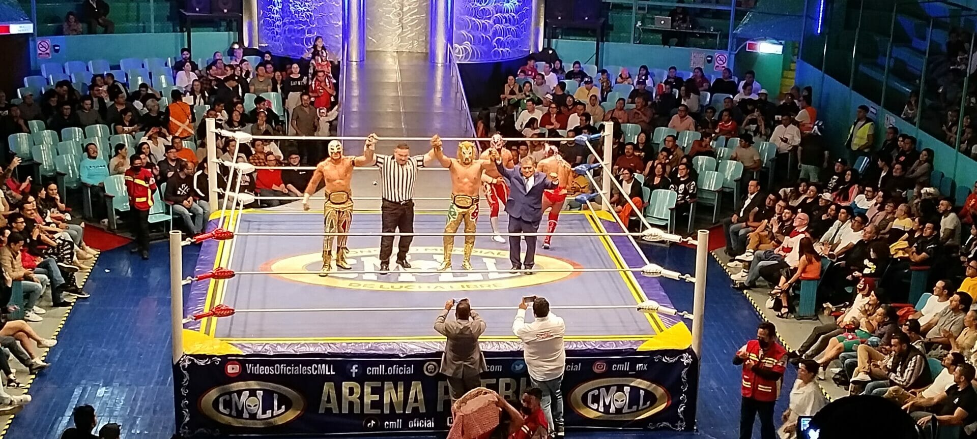 Una mirada de gente viendo un combate de lucha libre en una arena.