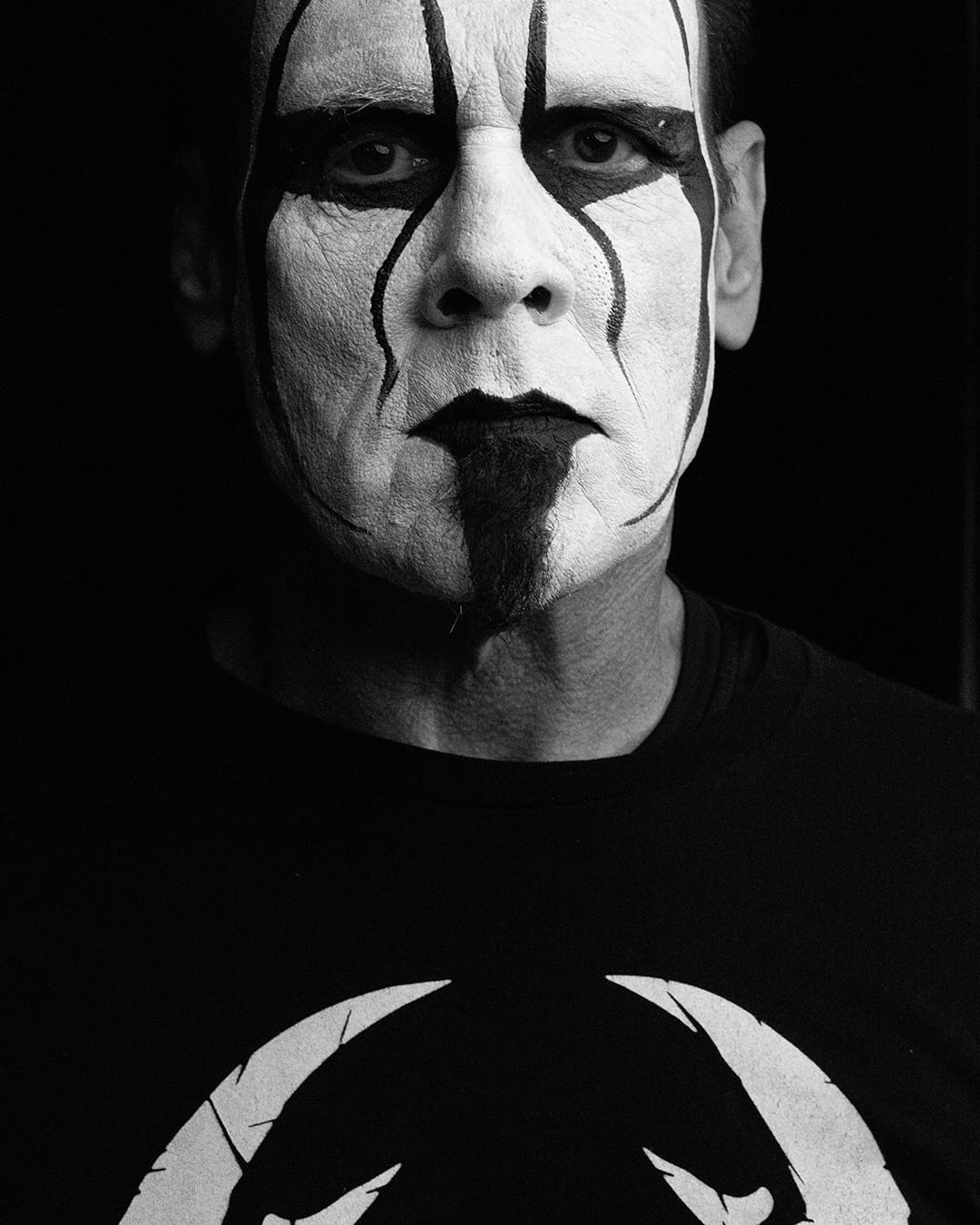 Superluchas - Una fotografía en blanco y negro de un hombre con pintura en el rostro que evoca La Emoción de Jim Ross.