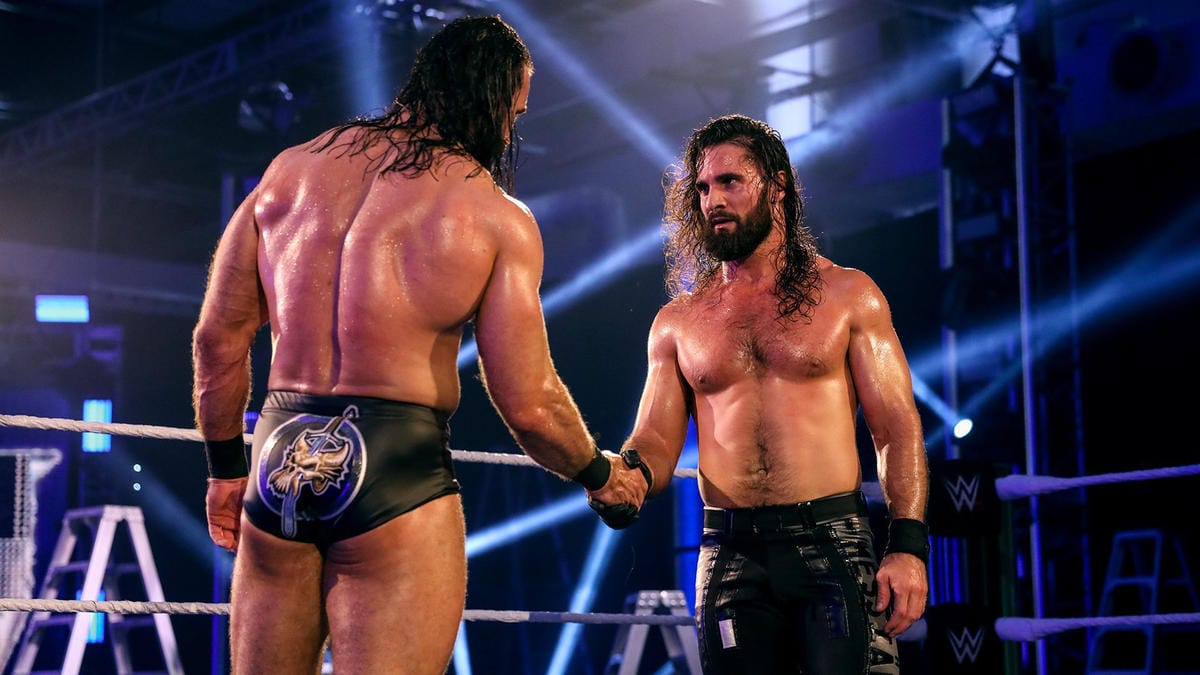Superluchas - Dos luchadores, Drew McIntyre y Seth Rollins, dándose la mano en un ring de lucha libre.