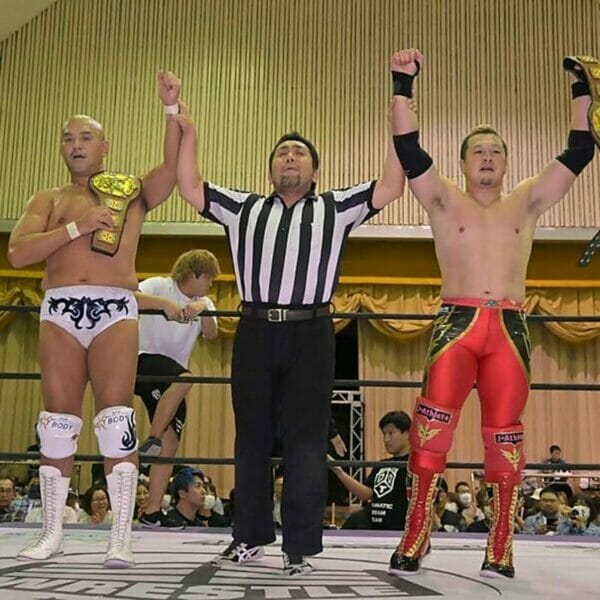 Superluchas - Un grupo de luchadores con las manos levantadas en el aire celebrando su victoria en el campeonato de DDT.