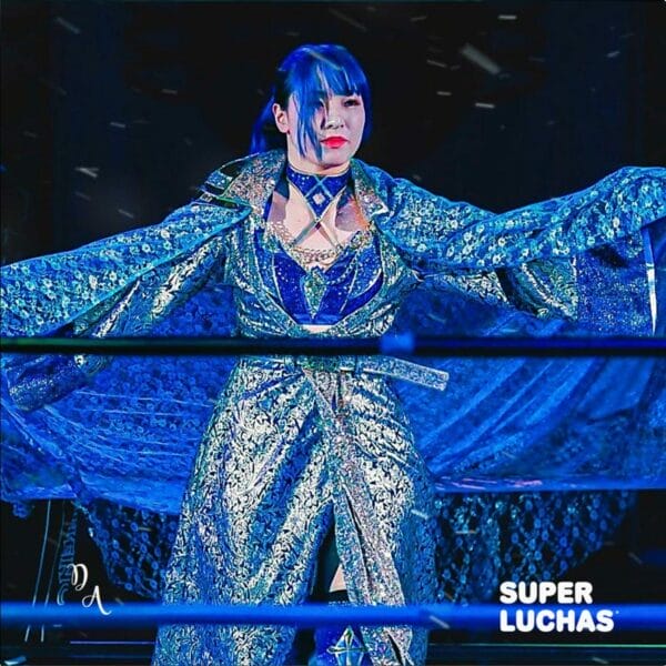 Superluchas - Risa Sera, vestida de azul, está parada en un ring de lucha libre.