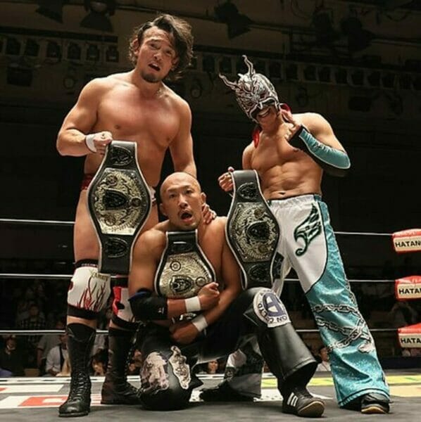 Superluchas - Tres luchadores de Dragon Gate posando para una fotografía en un ring de lucha libre.