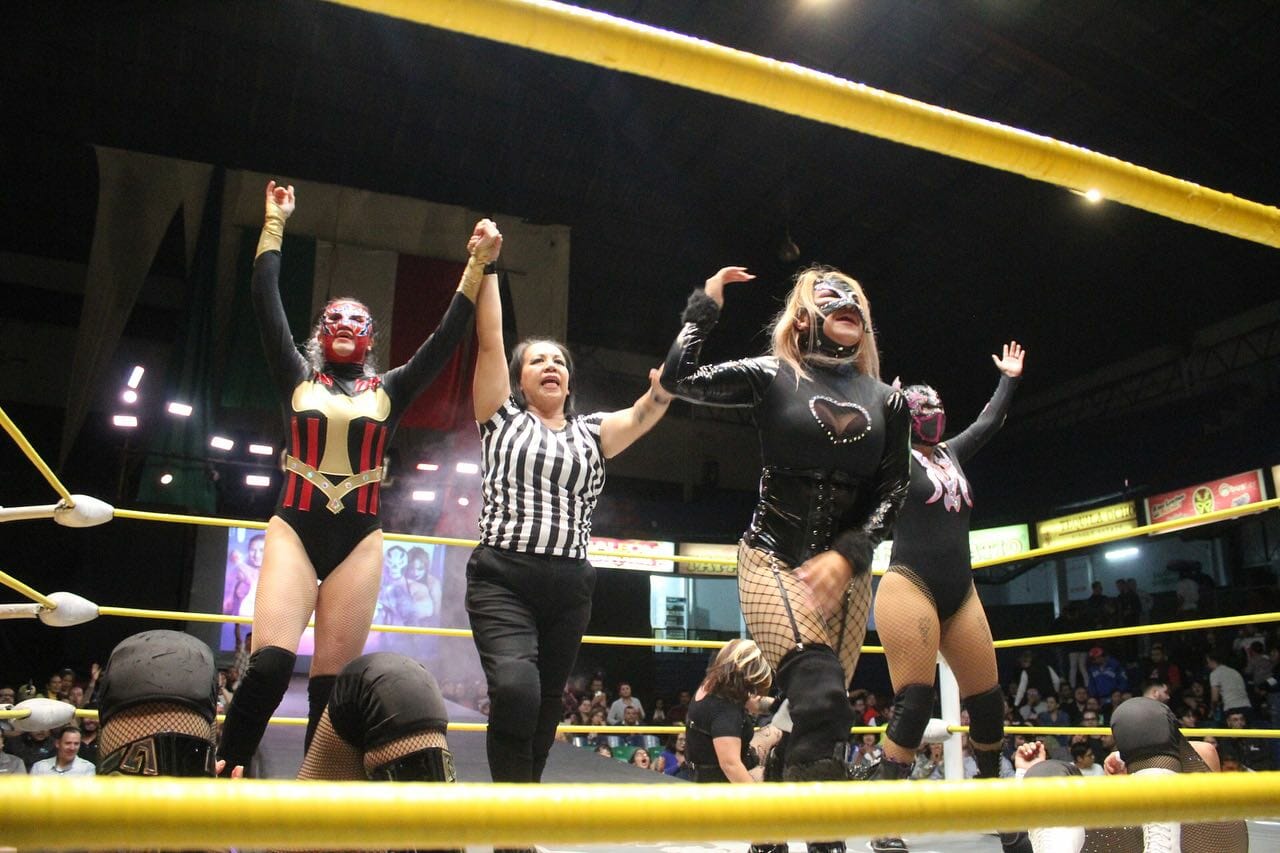 Superluchas - Un grupo de mujeres avasalladoras luchando en un ring con La Catalina como árbitro.
