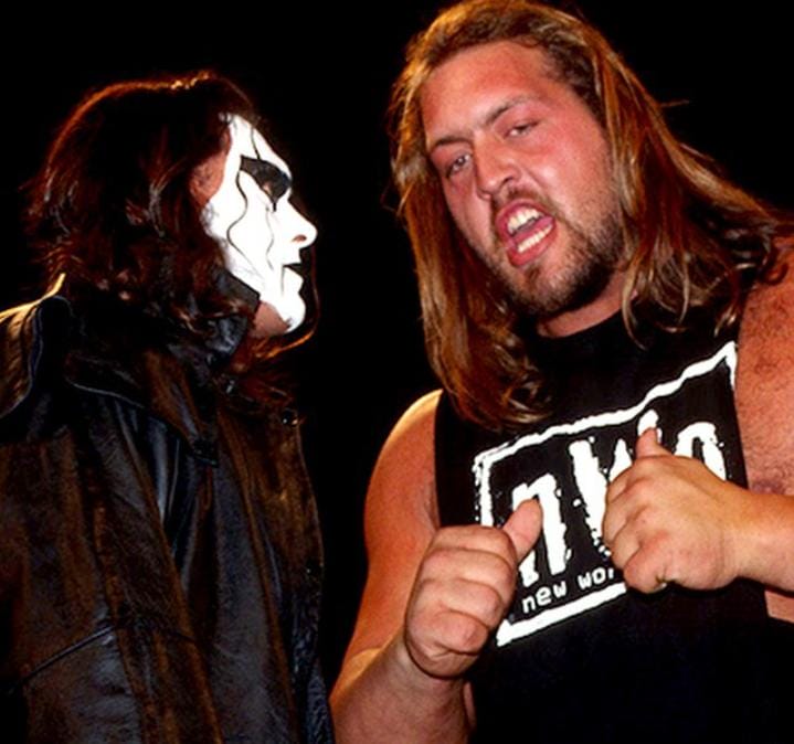 Superluchas - Dos luchadores con máscaras uno al lado del otro mientras Paul Wight cuenta una anécdota de Sting: "Le debo $5".