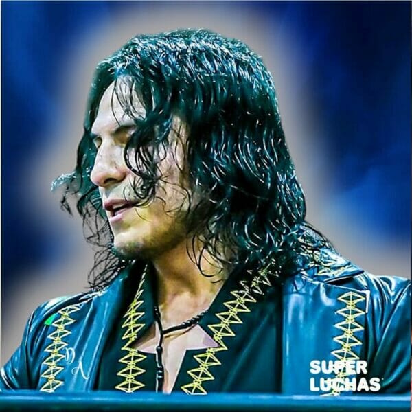 Superluchas - Un hombre con cabello largo está parado frente a un fondo azul en Dragon Gate: Adiós Diamante.