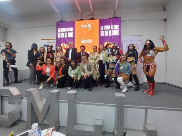 Superluchas - Un grupo de personas posando para una fotografía frente a un mural en honor a las Amazonas del CMLL en la Arena México.