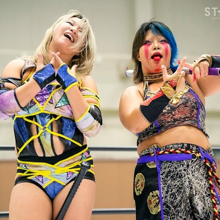 Superluchas - Dos luchadoras que participan en la "Goddess of Stardom Tag League" paradas una al lado de la otra en un ring de lucha libre.