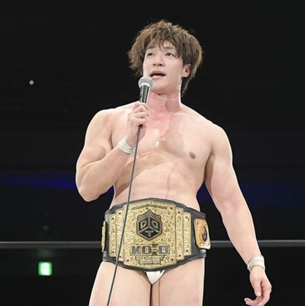 Superluchas - Yuki Ueno, el recién coronado campeón, sostiene con confianza un micrófono y su cinturón de campeonato.