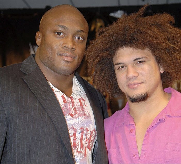Superluchas - Dos hombres posando para una foto uno al lado del otro durante el combate Carlito vs. Bobby Lashley en WWE, 16 años después.