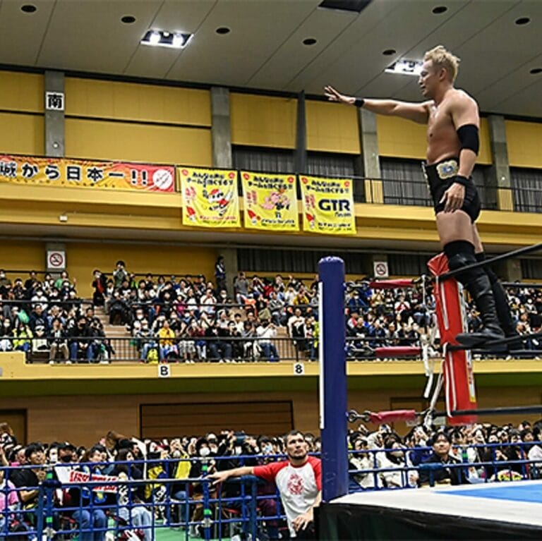 Superluchas - Un luchador parado encima de un ring en una arena, defendiendo el título de tercias de NJPW durante el evento "Anjo Rainy Days".