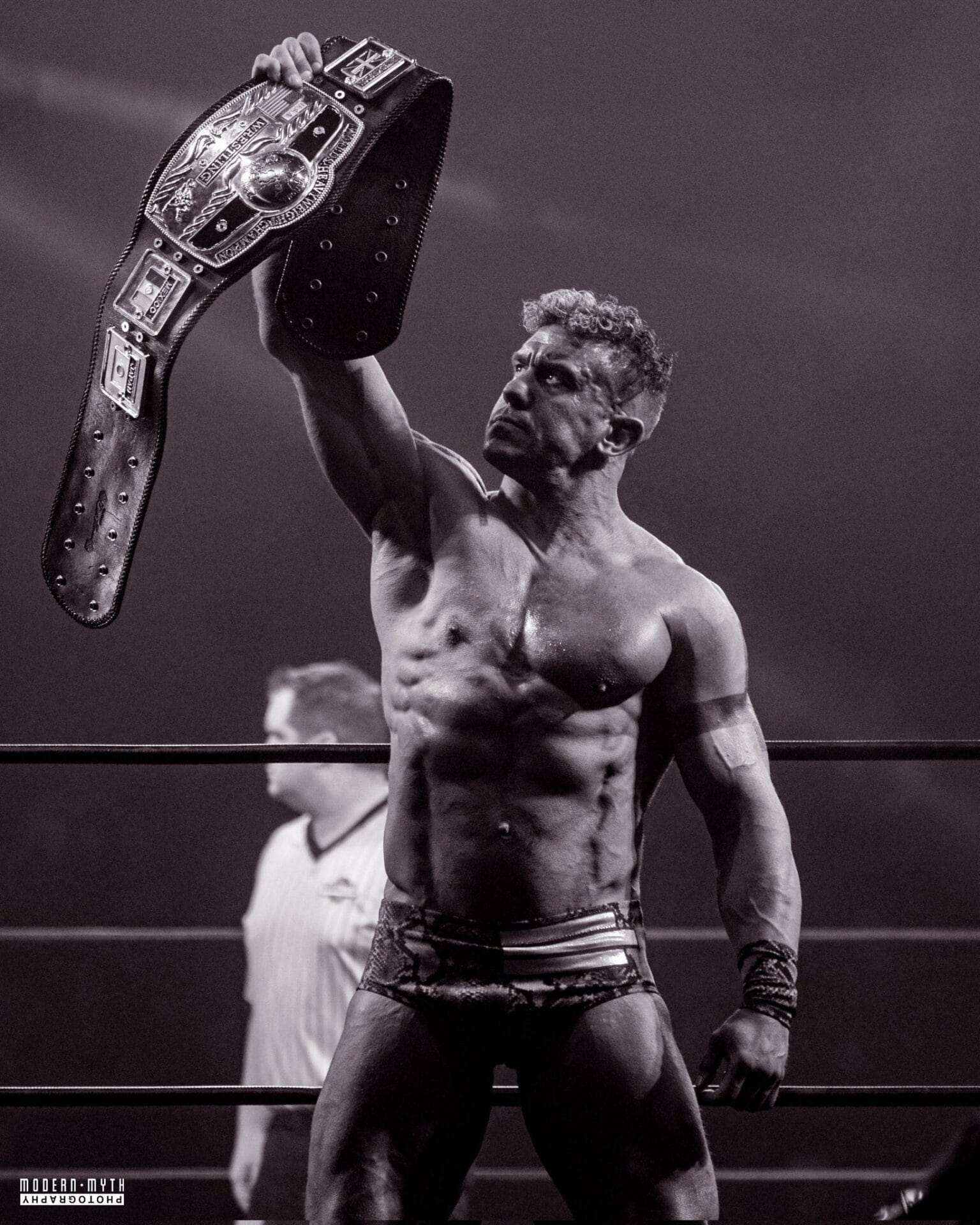 Superluchas - Un luchador victorioso en un ring de lucha libre, sosteniendo un cinturón de campeonato.