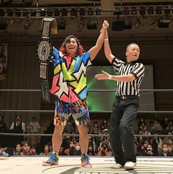 Superluchas - Dos luchadores, Hiromu Takahashi y su oponente, celebran con sus cinturones en un ring de lucha libre después de que Hiromu se hiciera con el codiciado Campeonato Iron Man Heavy Metal.