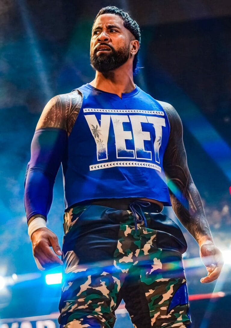 Superluchas - Jimmy Uso, vestido con una camiseta azul, se encuentra en el escenario junto a Seth Rollins, cumpliendo los deseos de Jey Uso.