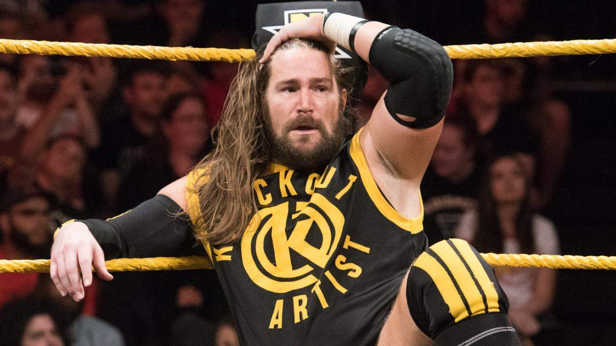 Superluchas - Palabras clave: luchador, pelo largo.Descripción: Un luchador de pelo largo, Chris Hero, sentado en el ring.
