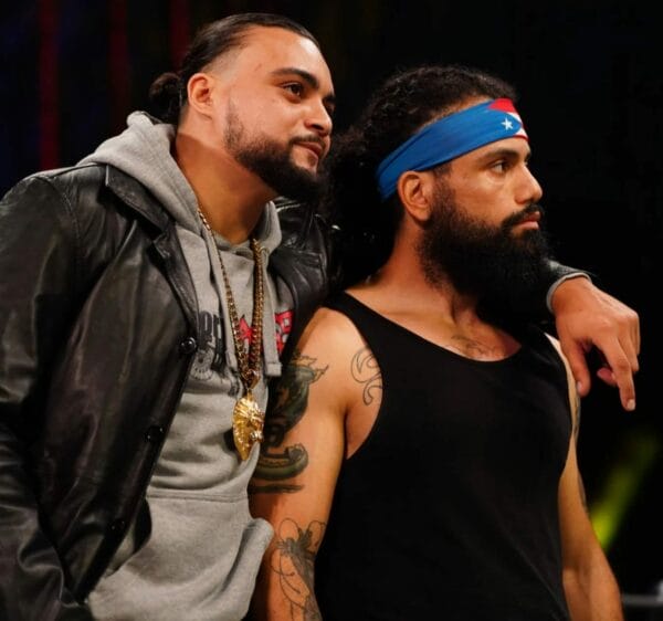 Superluchas - Dos hombres barbudos, Sammy Guevara y otro individuo, uno al lado del otro.