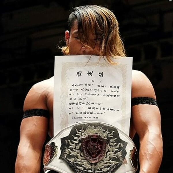 Superluchas - Un luchador de Dragon Gate sostiene triunfalmente un trozo de papel.