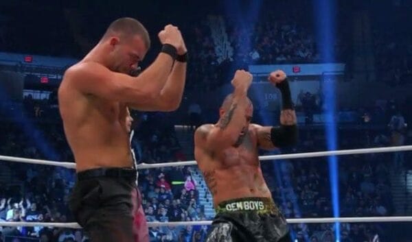 Superluchas - Dos luchadores, Danielson y Briscoe, con las manos levantadas en el aire.