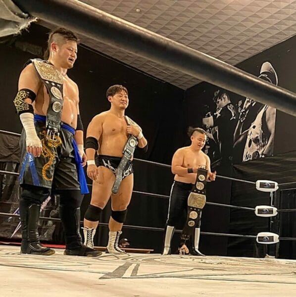 Superluchas - Un grupo de luchadores de pie en un ring de lucha libre durante el evento Primera defensa del cetro de tercias de Yokohama de BJW.