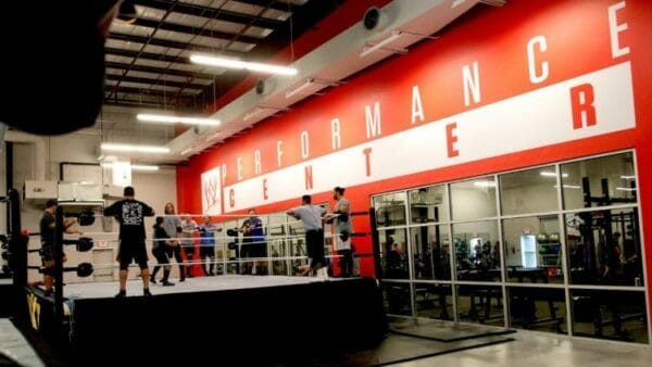 Superluchas - Ace Steel's experience as a coach at the WWE Performance Center, where a group of people meet in a gym with a poster that says Performance Center.