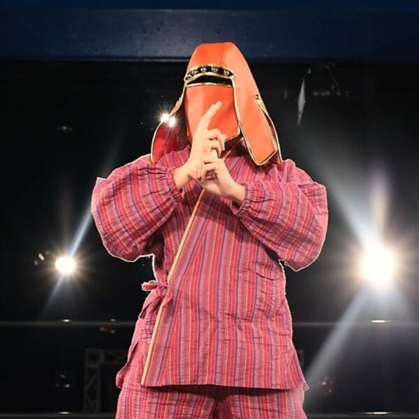 Superluchas - Un luchador con un traje rojo parado en un escenario, NOAH