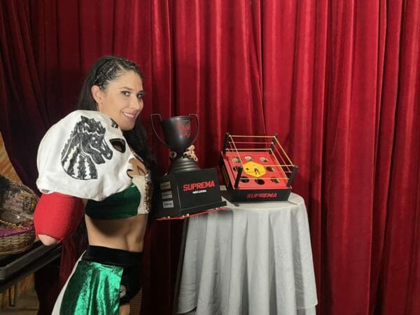Superluchas - Julissa, vestida de luchadora, sostiene triunfalmente su segundo trofeo tras ganar el torneo "Suprema" en México.