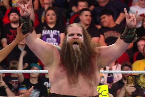 Superluchas - Akira Tozawa, un hombre con barba, levanta las manos en el aire.