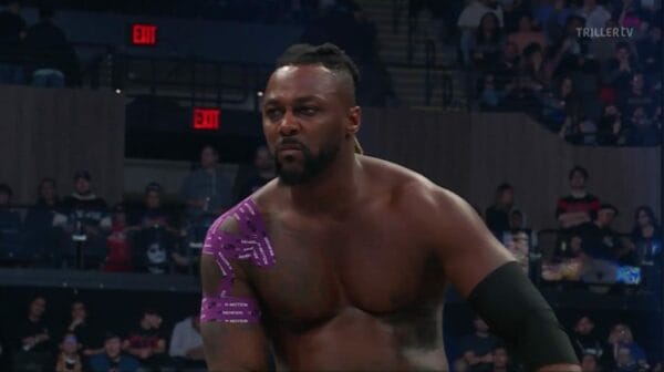 Superluchas - Swerve Strickland, con tatuajes morados, se para con confianza frente a una multitud emocionada.