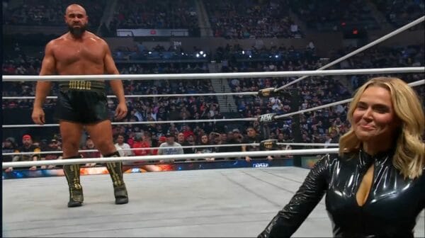 Superluchas - Una mujer está de pie junto a un luchador, Miro, en un ring de lucha libre.