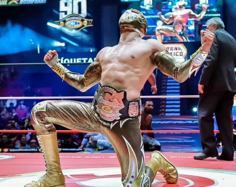 Superluchas - Máscara Dorada, luciendo un traje dorado, se encuentra posando triunfalmente en el ring luego de convertirse en el Campeón Histórico Welter NWA.
