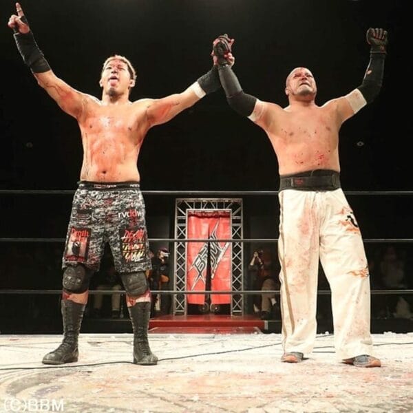 Superluchas - Dos luchadores de BJW con los brazos en alto, celebrando su victoria en un torneo de combate a muerte.