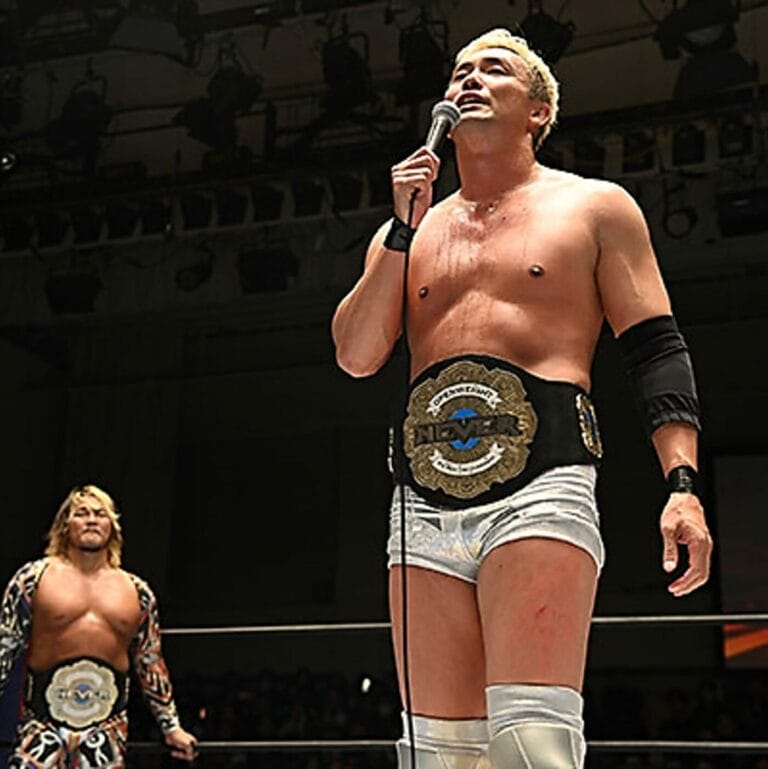 Superluchas - Un luchador ofrece una emotiva despedida de Okada sosteniendo un micrófono mientras está de pie junto a otro luchador en NJPW.