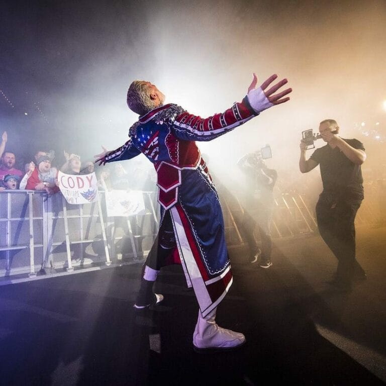 Superluchas - Cody Rhodes, un luchador con los brazos extendidos frente a una multitud, mostrando su histórica victoria en WWE 2K25.
