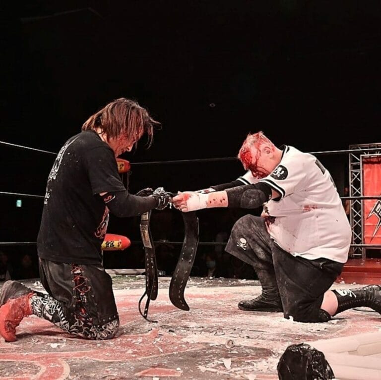 Superluchas - Yuki Ishikawa y el luchador de BJW participando en un campeonato, arrodillados en un ring de lucha libre.