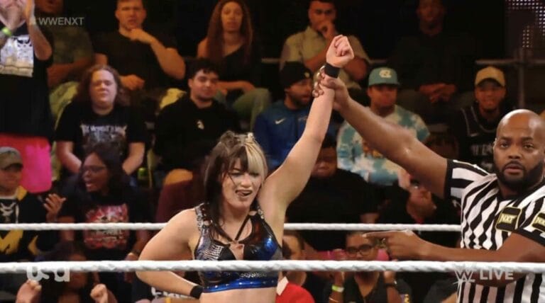 Superluchas - En enero de 2024, un árbitro de WWE NXT levanta triunfalmente la mano de una mujer frente a una multitud entusiasta.