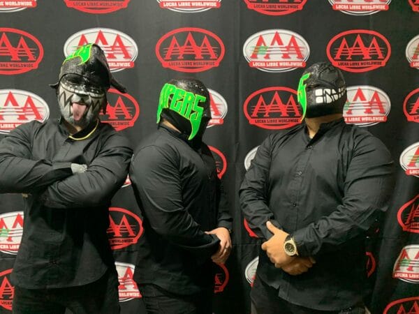 Superluchas - Tres víboras con máscaras negras y verdes paradas frente a una pared durante la guerra.