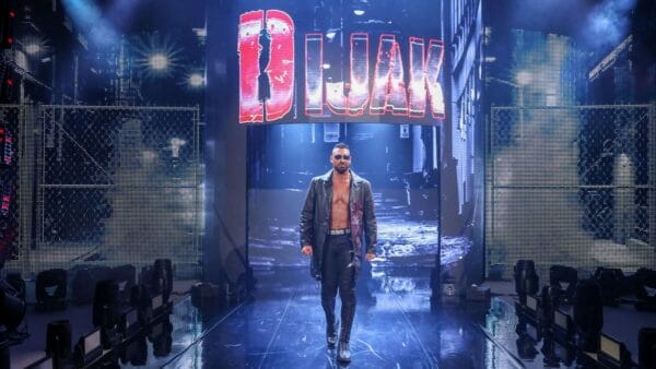 Superluchas - Un hombre, vestido de negro y dorado, caminando por una pasarela con un cartel que dice b blak.