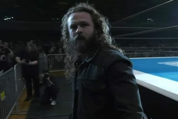 Superluchas - Jack Perry, con cabello largo, parado frente a un ring de lucha libre como parte de su contrato con AEW.