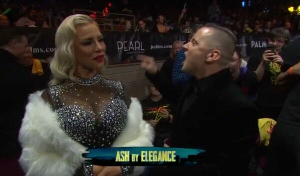 Superluchas - Una mujer, Dana Brooke, está hablando con un hombre en la alfombra roja del evento TNA Hard to Kill.