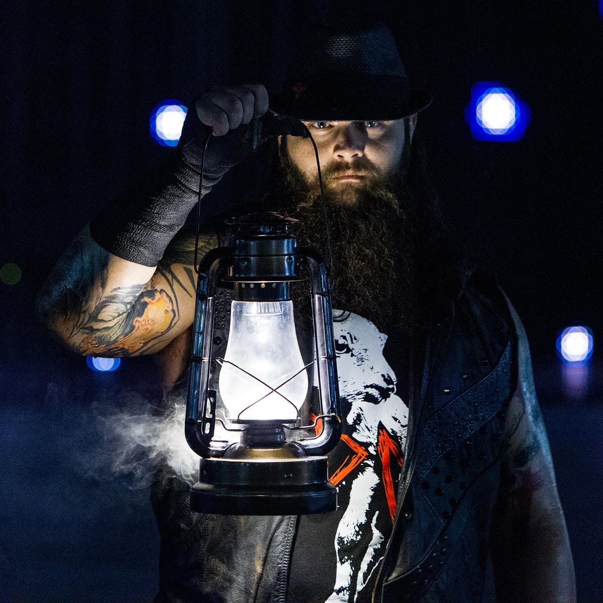 Superluchas - Bray Wyatt, un hombre barbudo de la WWE, sosteniendo una linterna de la que sale humo como parte de su misterioso proyecto.