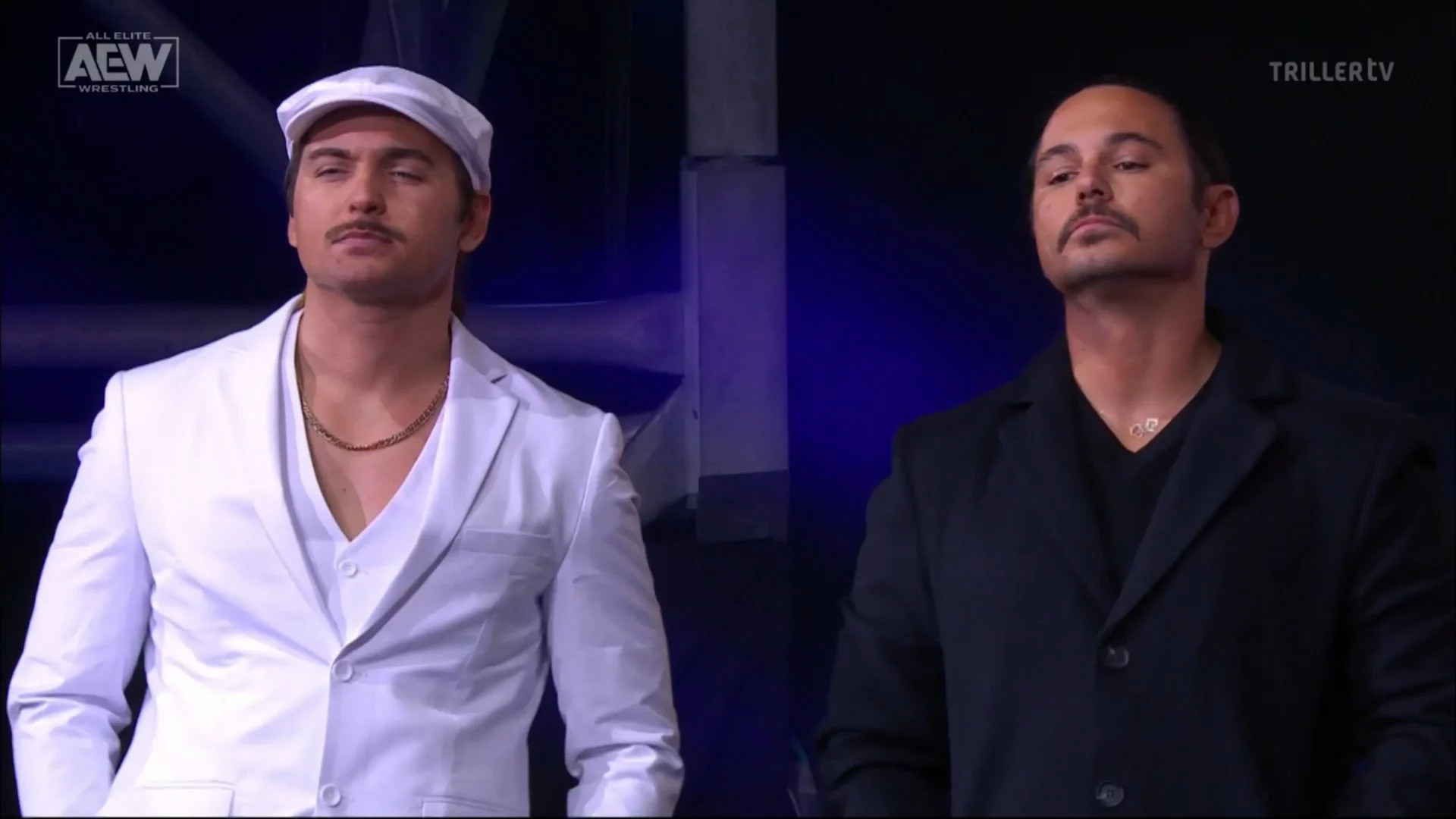 Superluchas - Dos hombres con trajes blancos, Sting y Young Bucks, uno al lado del otro.